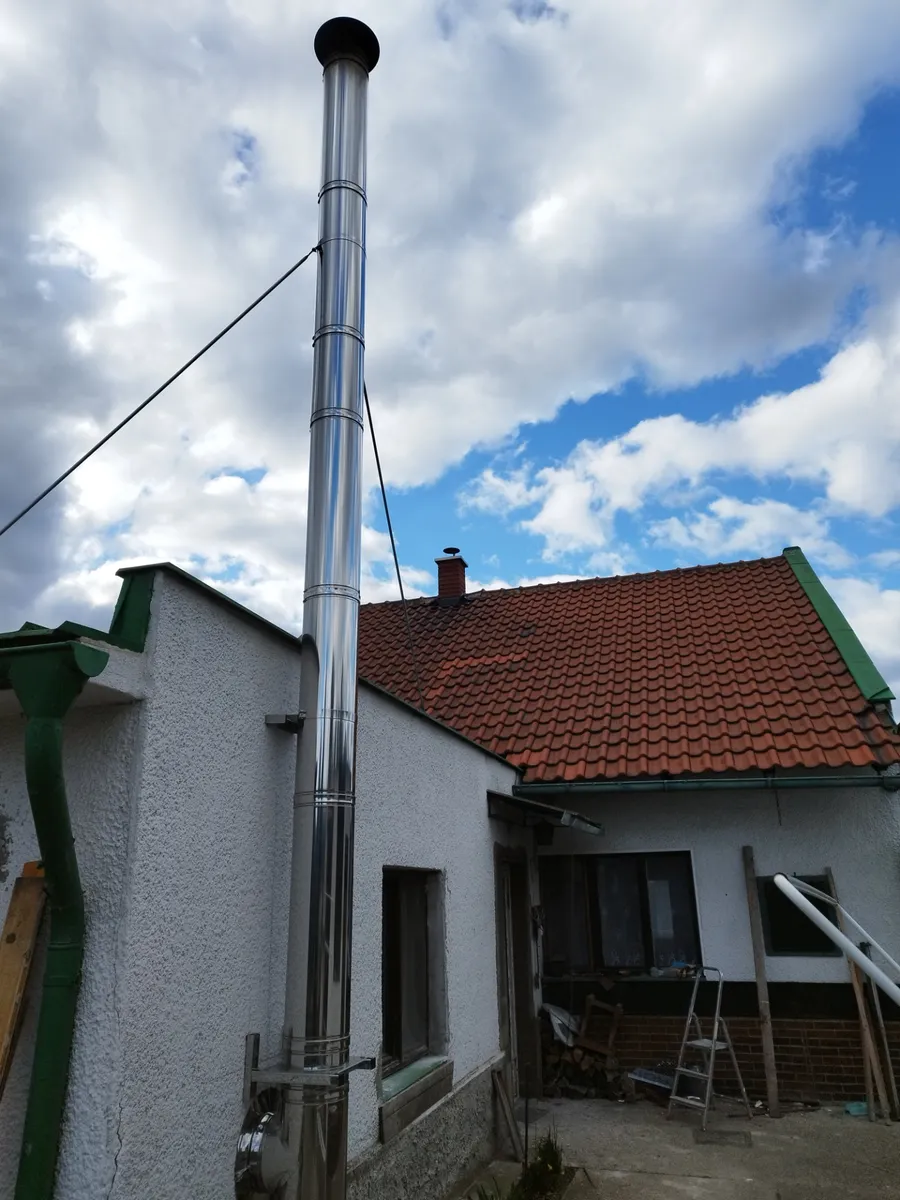Nerezový komín vedený po fasádě bílého rodinného domu