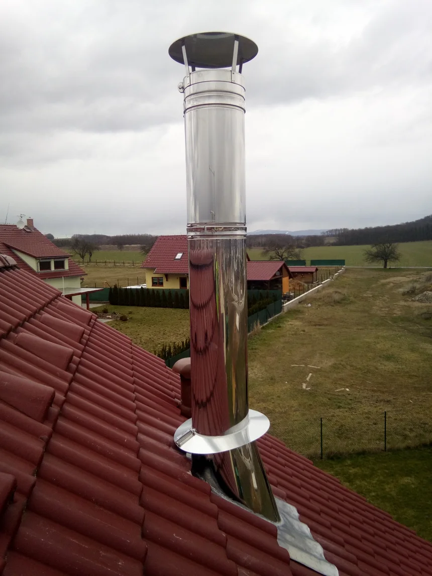 Nerezový komín vyvedený nad taškovou střechou rodinného domu na Mělnicku